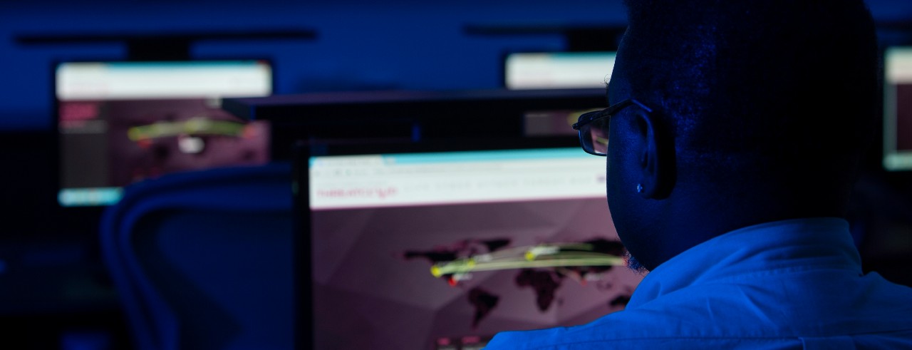 Dark blue screens in a computer lab with a shadow of a person watching the screens