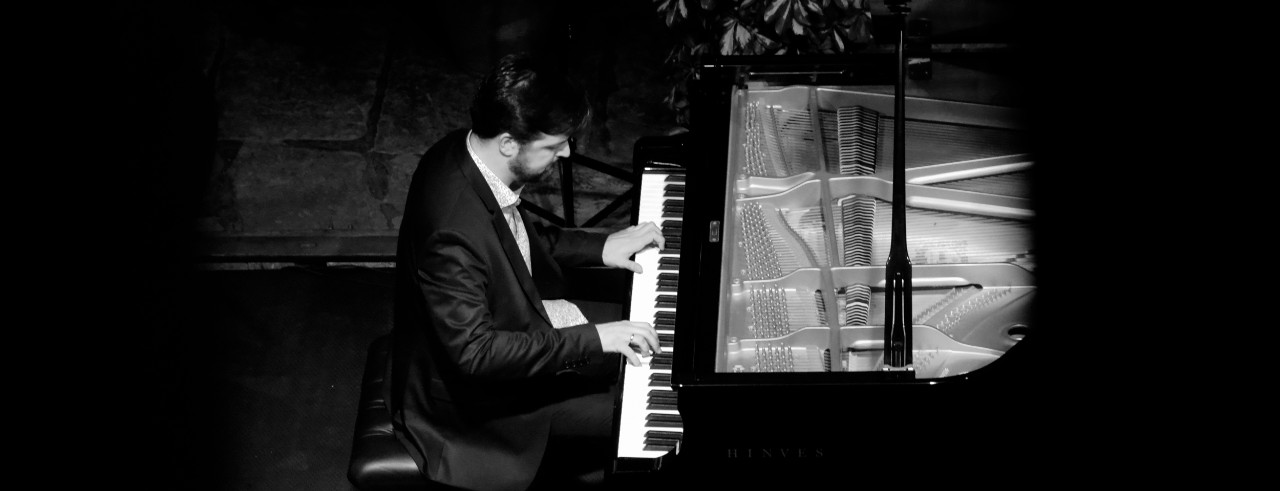 A black and white photo of CCM Assistant Professor of Jazz Piano Sergio Pamies playing piano.