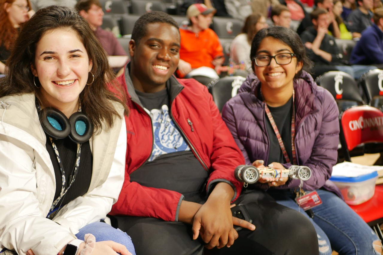 Three students at Fifth Third Arena, one student holding a robot