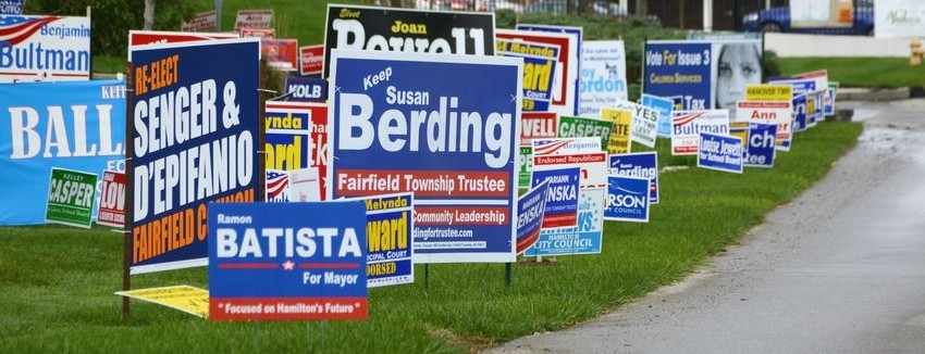 many different campaign signs along a street.