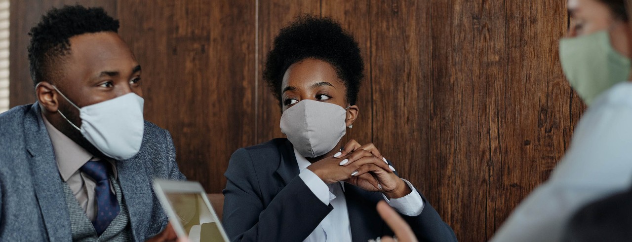 Three business people wearing masks during an in-person meeting.