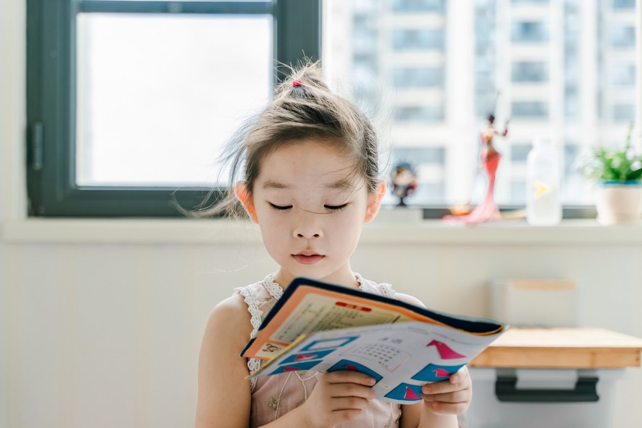 A young girl reading a magazine