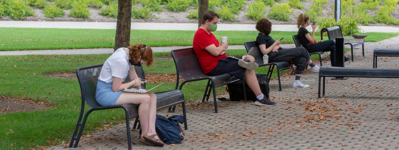 Students social distance by sitting singly on benches