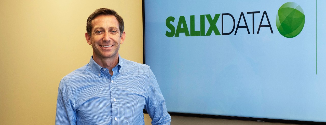 Volunteer award winner smiling in front of monitor with company logo