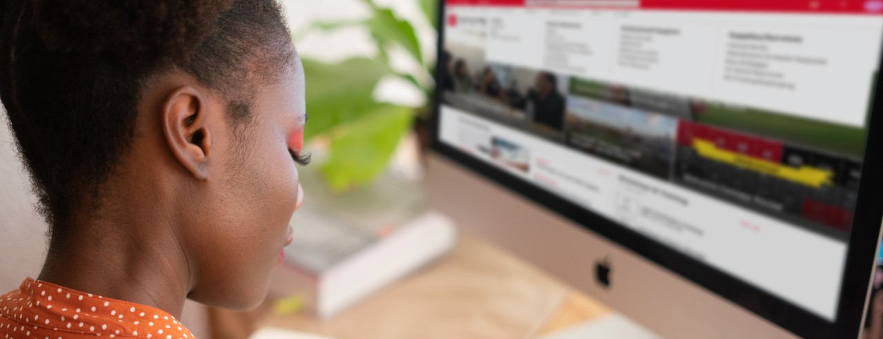 woman working on a computer with Bearcats Landing intranet homepage