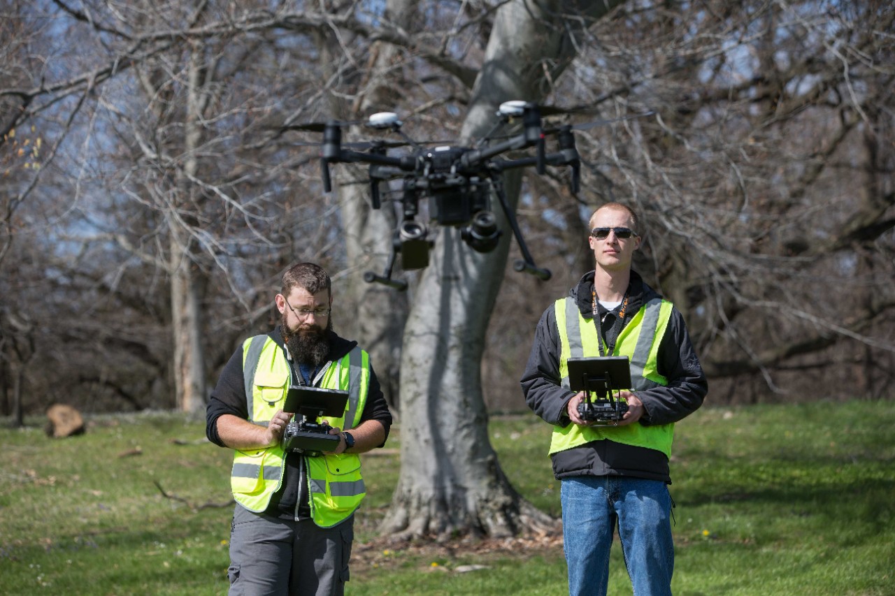 UC graduates operate a drone.