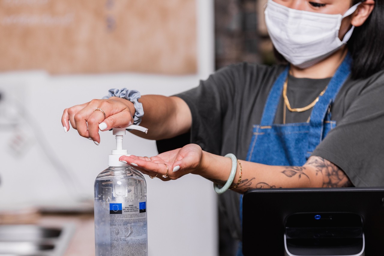 a woman wearing a mask uses hand sanitizer