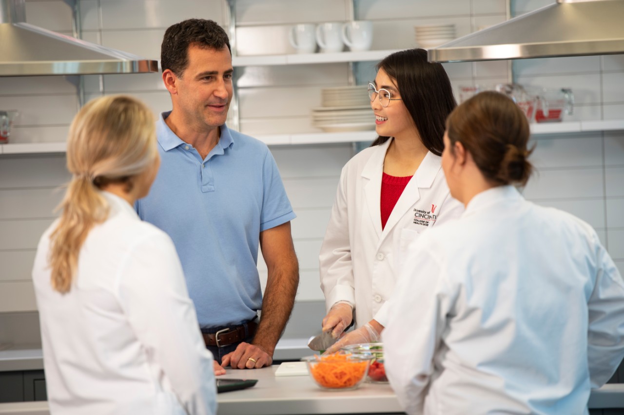 Dietetics professor with students in foods lab prepping vegetables