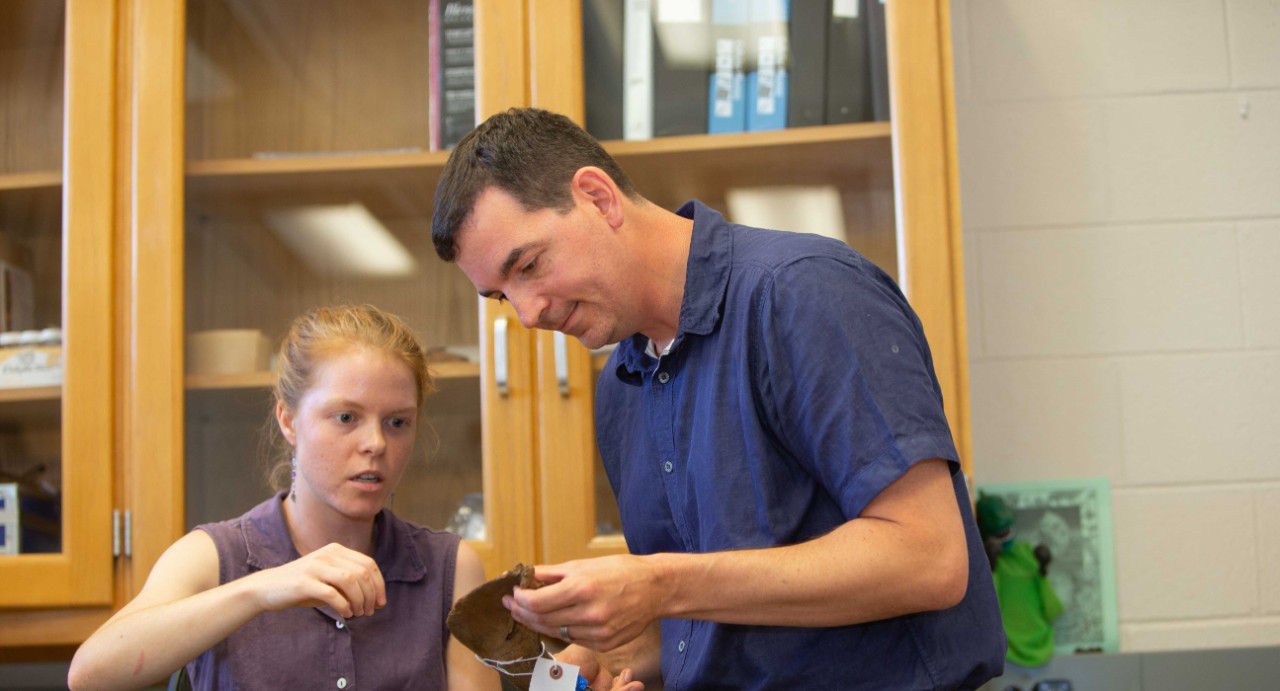 UC student Abby Kelly and UC assistant professor Joshua Miller study an ancient horse jawbone.