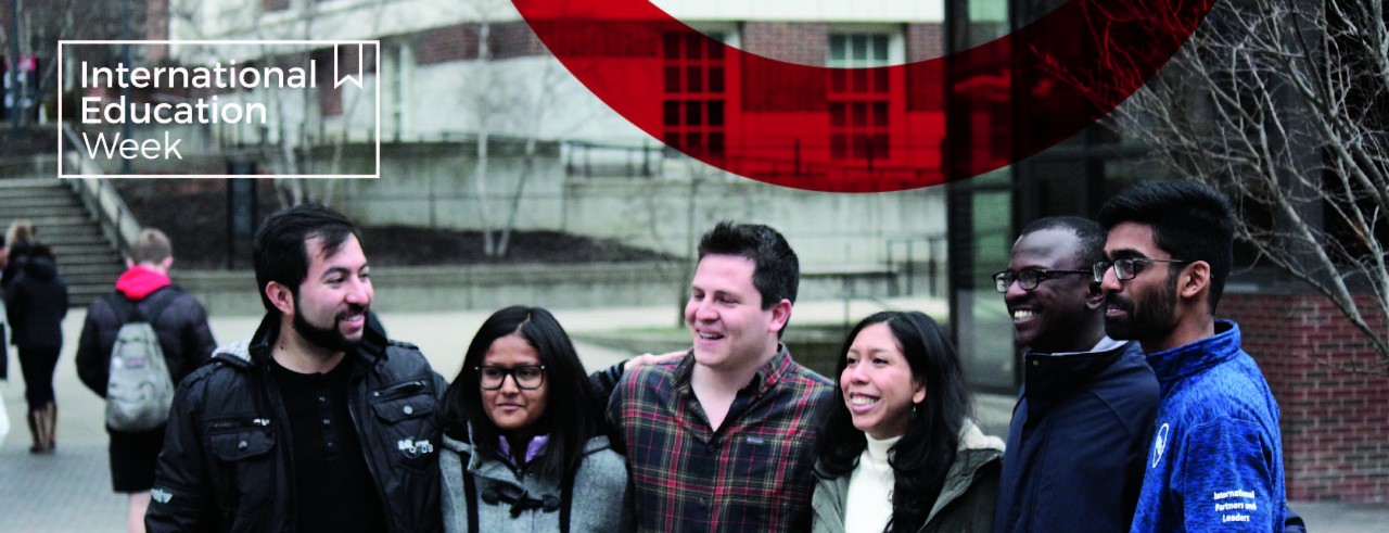 Six international students smile on campus. The International Education Week logo is visible.