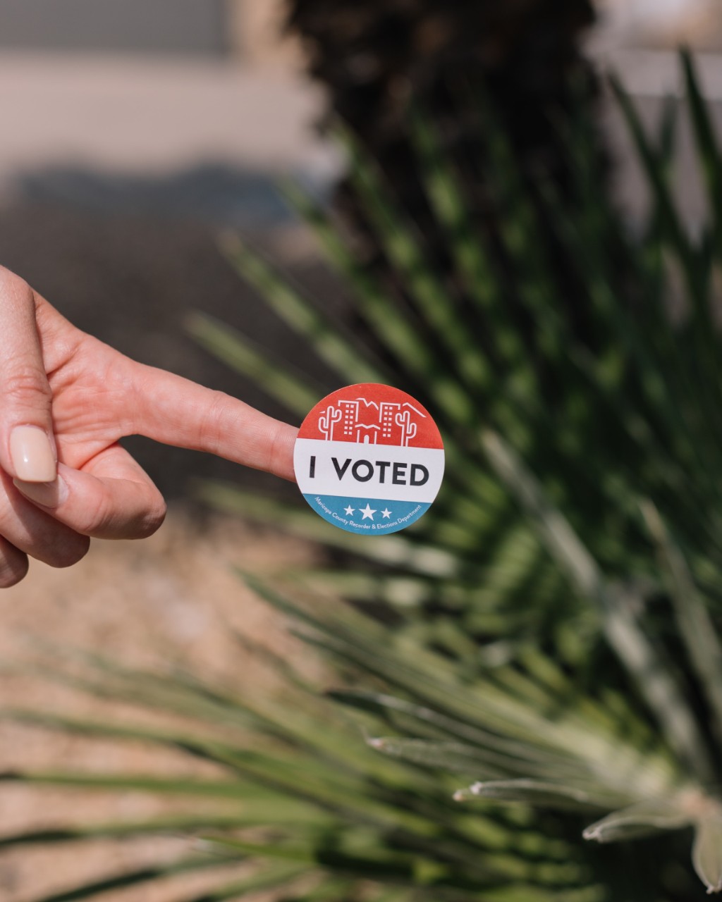 finger holding a voting sticker