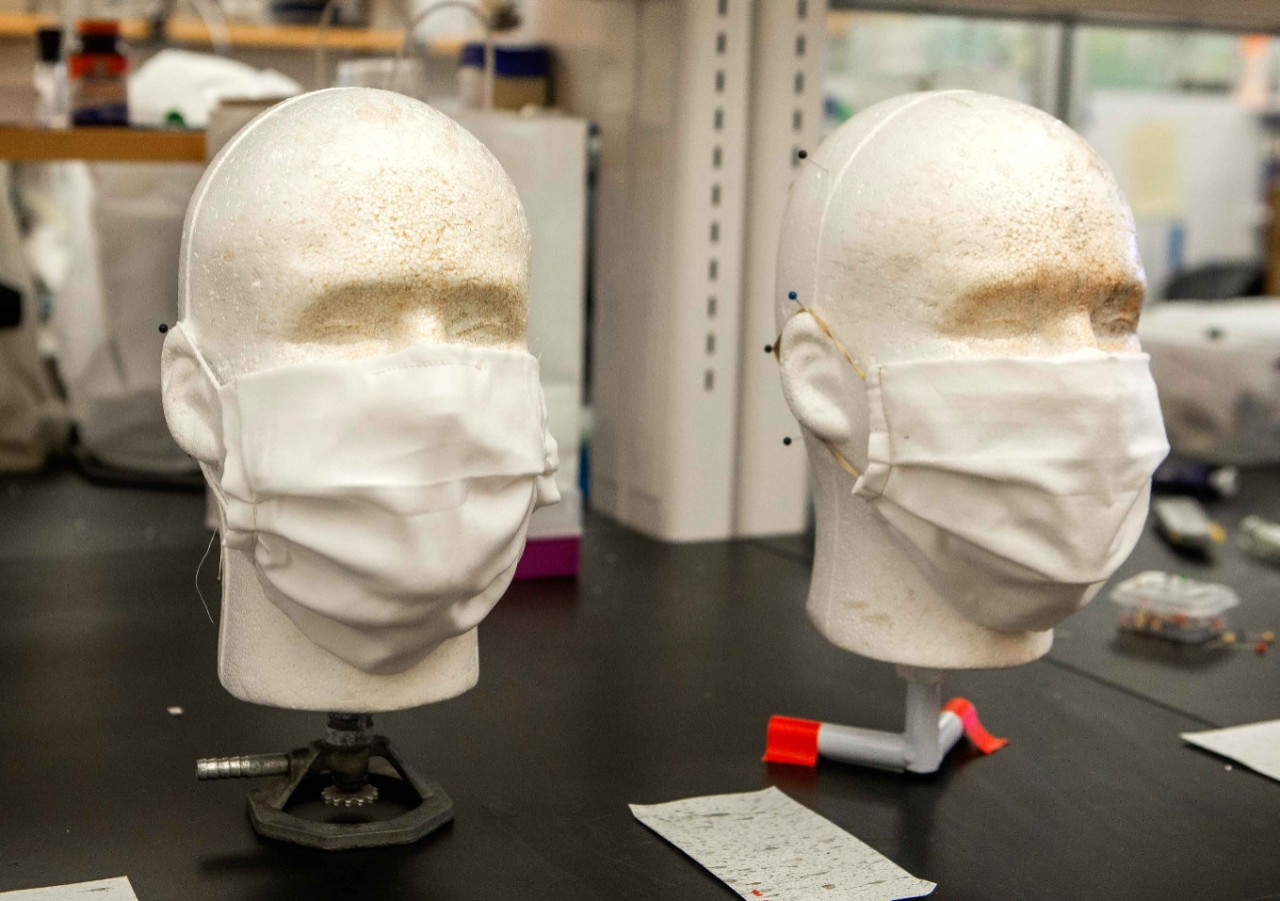 Mannequin heads on a lab bench wear silk face masks.