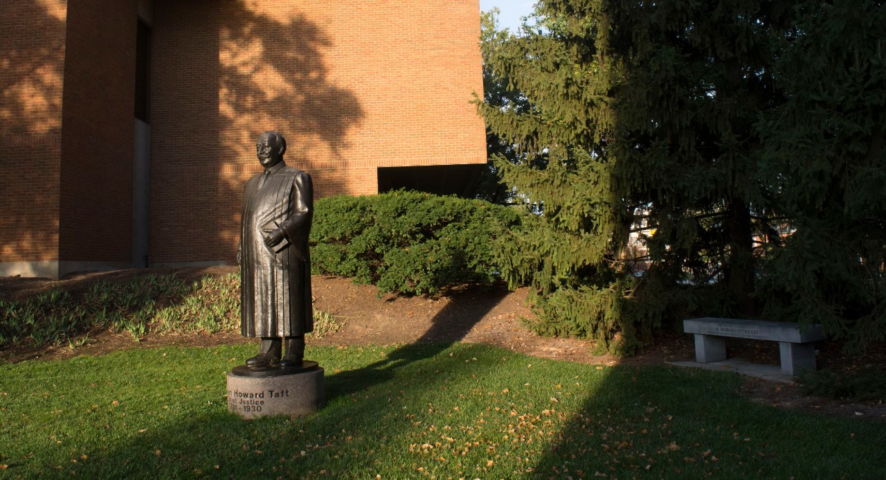 Brick building with statue of man in front on green grass