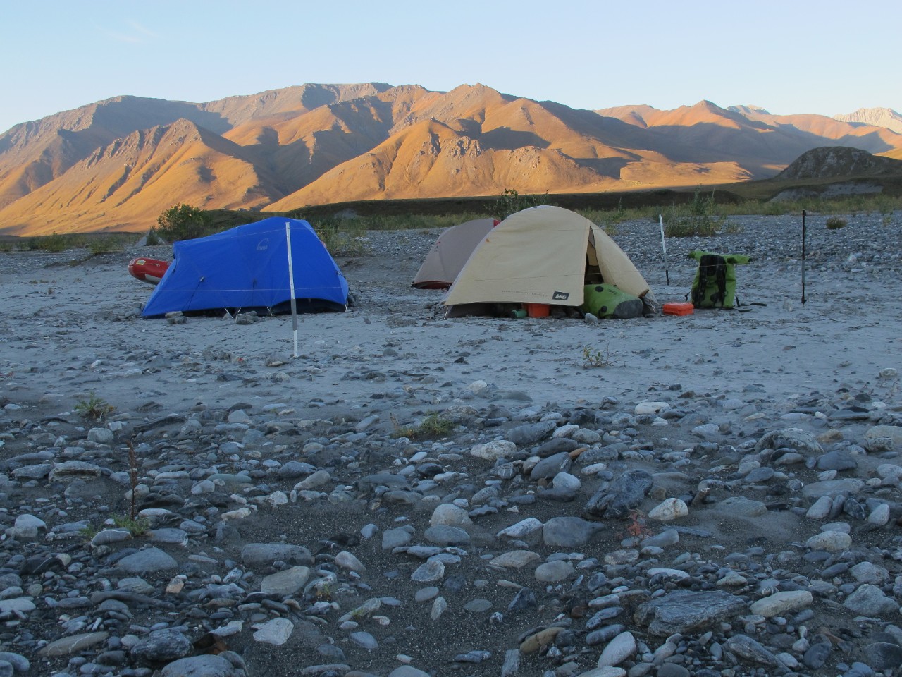 Tents are set up along a rocky riverbank in the Arctic National Wildlife Refuge.