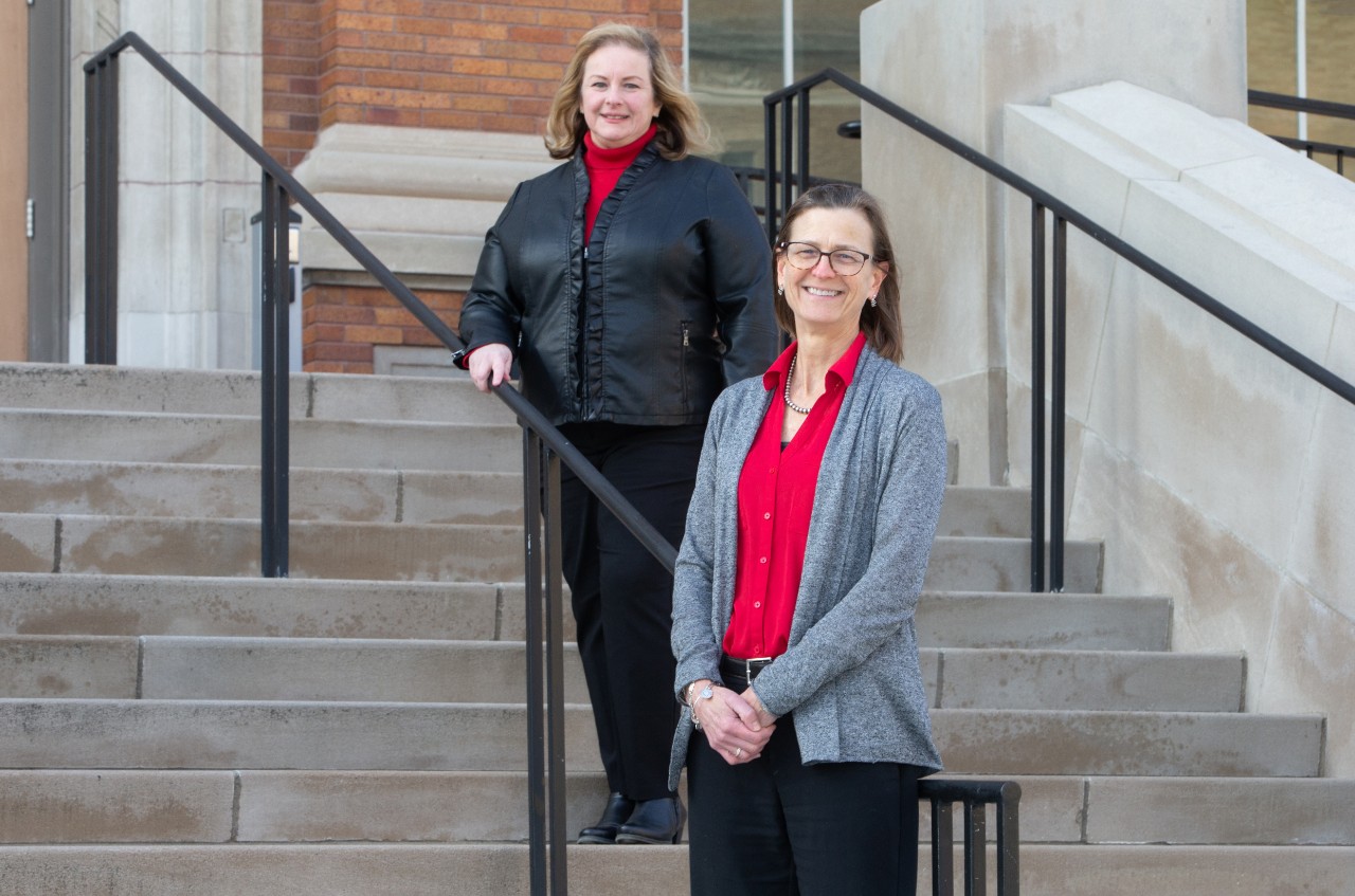 Two women standing on the exterior steps of a college building