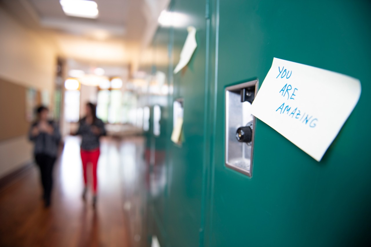 A locker in a high school hallway with a sticky note saying "you are amazing"