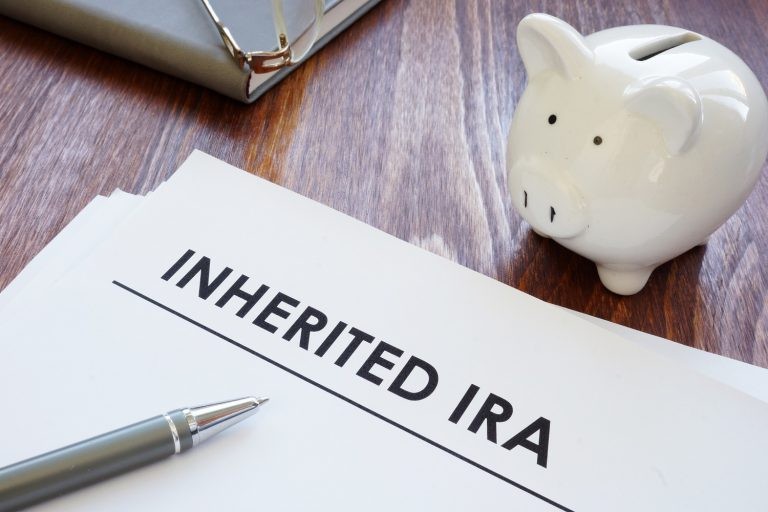 piggy bank next to page titled inherited ira with a pen