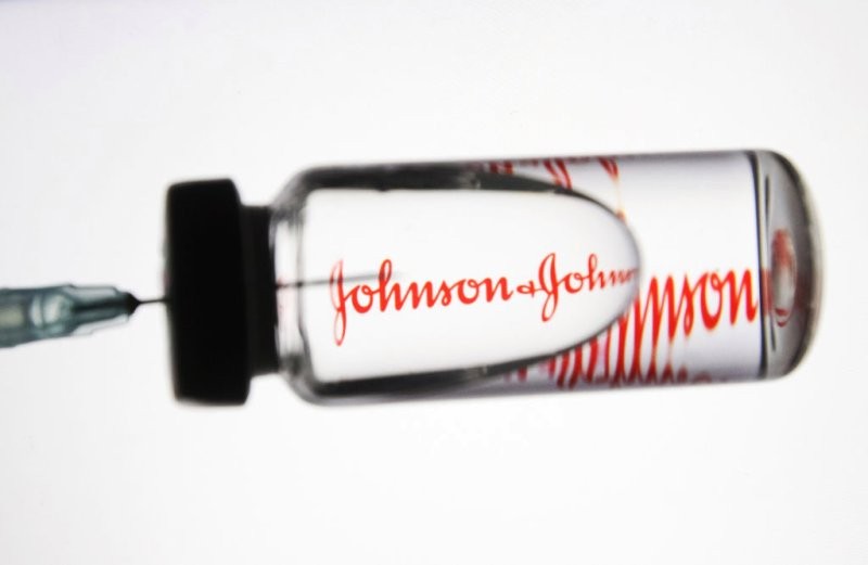 A close up of a syringe with the Johnson & Johnson logo in the background