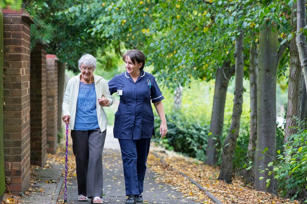 older woman walking with caregiver