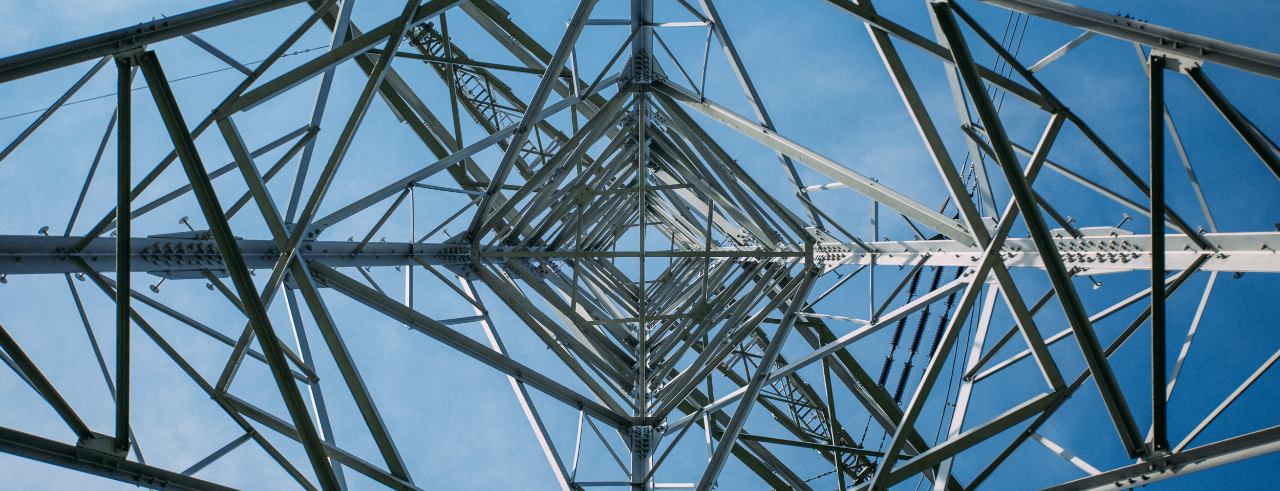 a view from the inside of an power line pylon, looking up at a blue sky