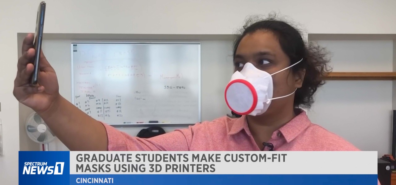 Shriya Patil holds up a phone while wearing a custom 3D-printed face mask.