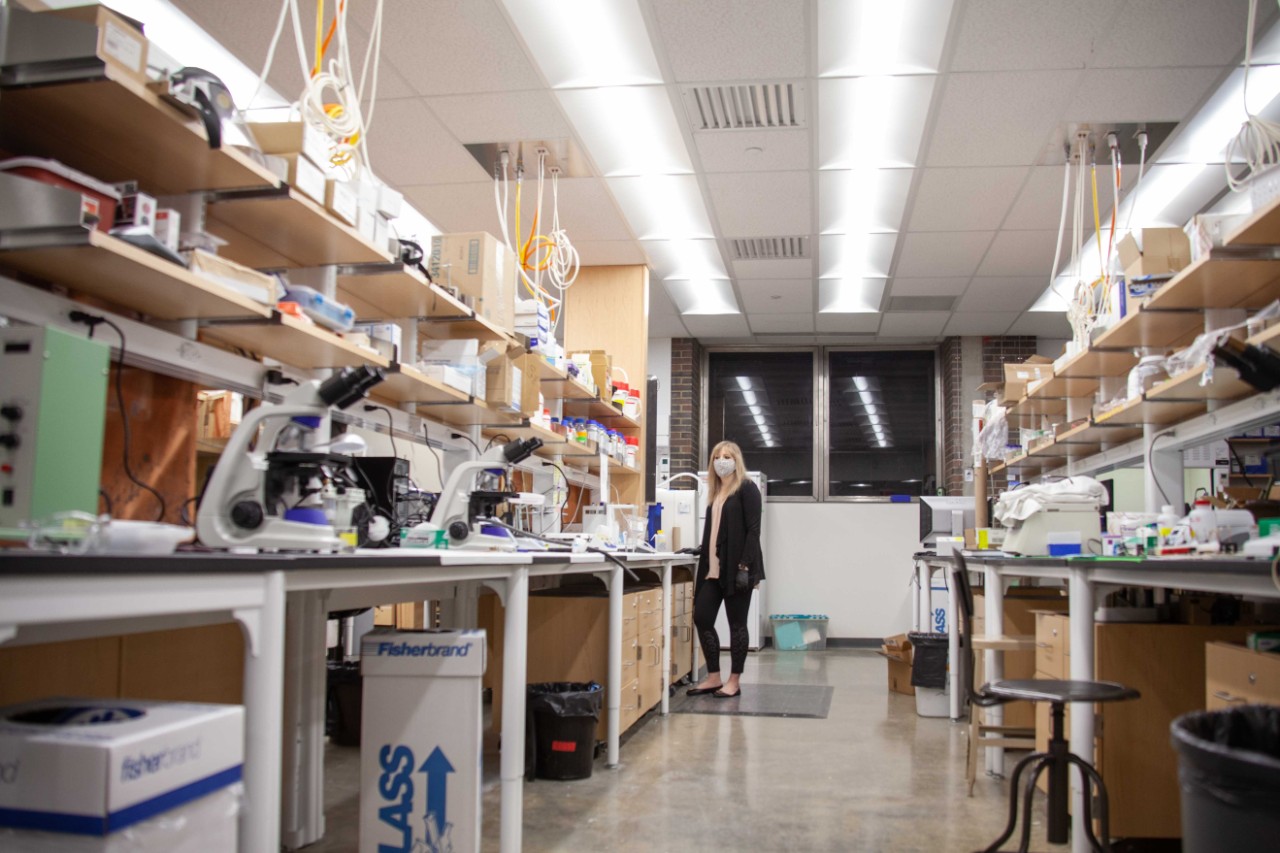 Ashley Ross wearing a face mask stands at the opposite end of her chemistry lab.