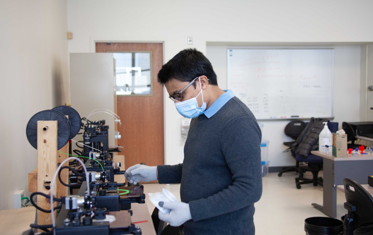 UC College of Engineering and Applied Science doctoral student Aditya Desphpande oversees the printing of a custom face mask in UC's Digital Fabrication Lab. 