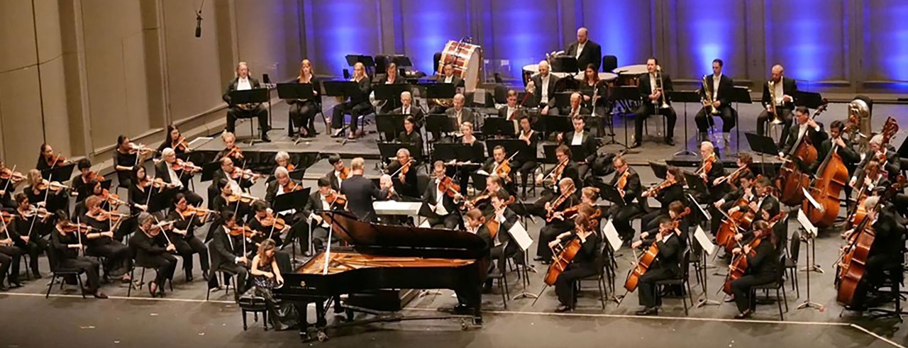 A pianist performs on stage with an orchestra