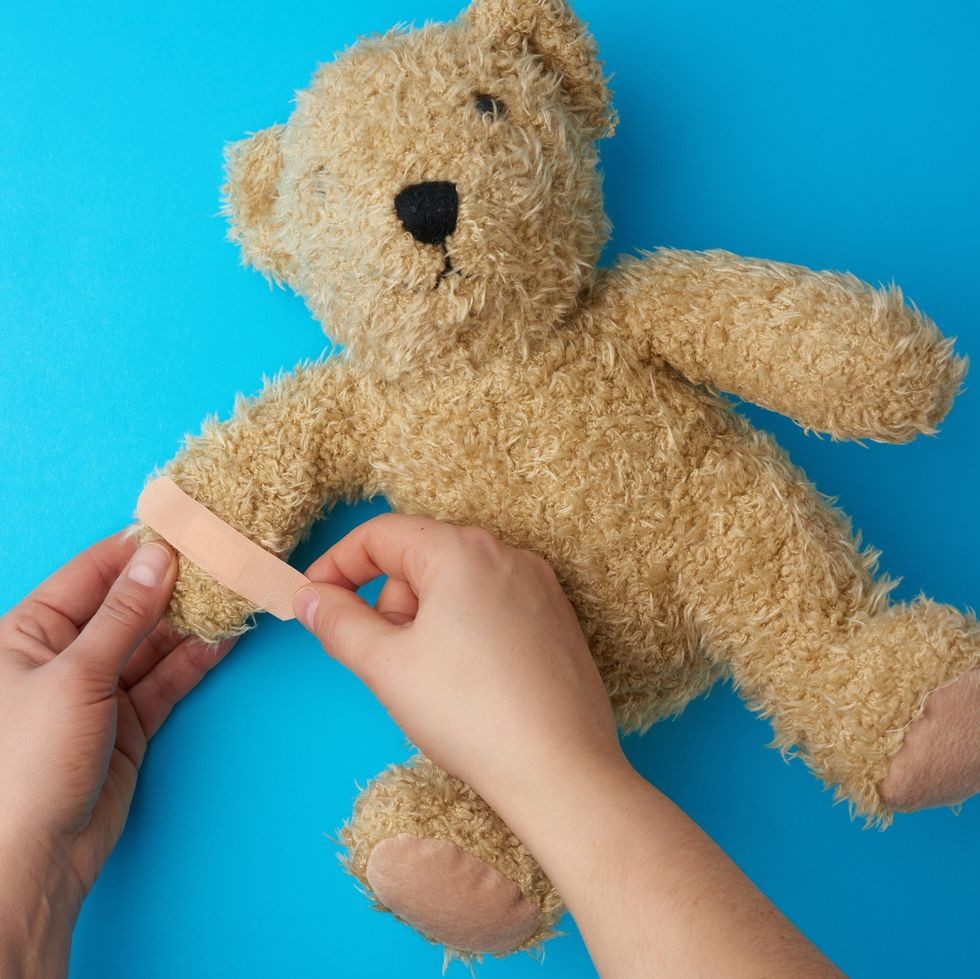 a person putting a bandage on a teddy bear