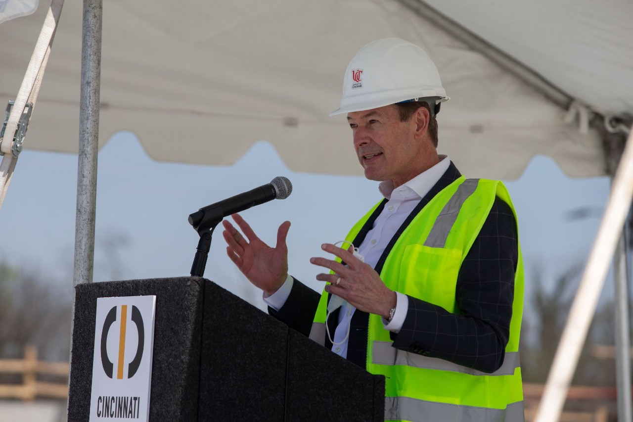 A man in a hardhat and safety vest stands at a podium.