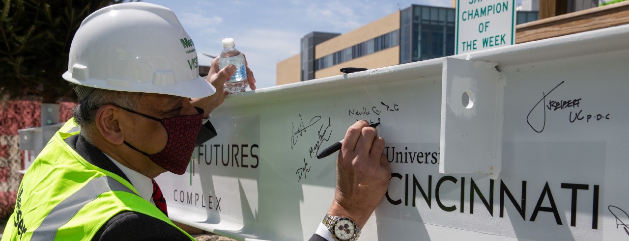 UC President Neville Pinto signs the last steel beam for the new Digital Futures Building.