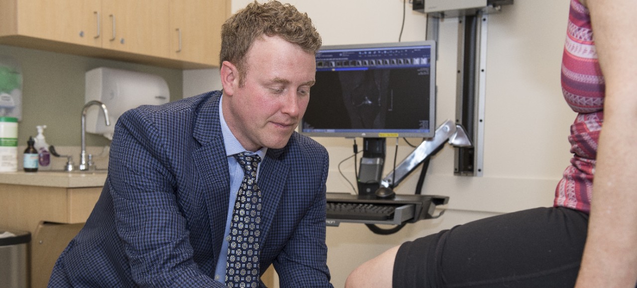 UC Health orthopedic surgeon examines a patient's knee