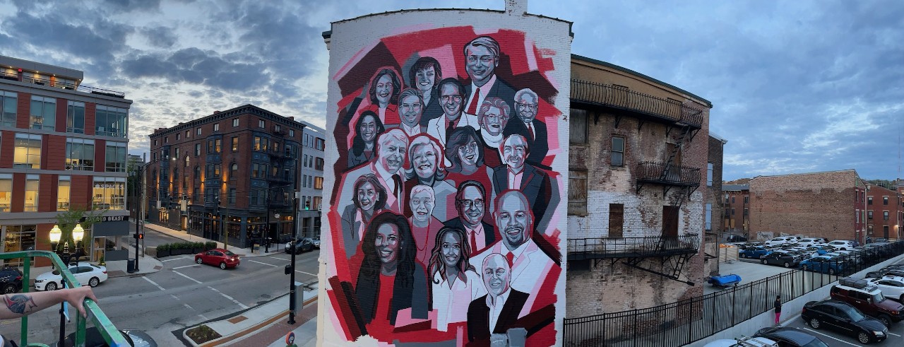 Urban mural with red and black collage of 19 portraits