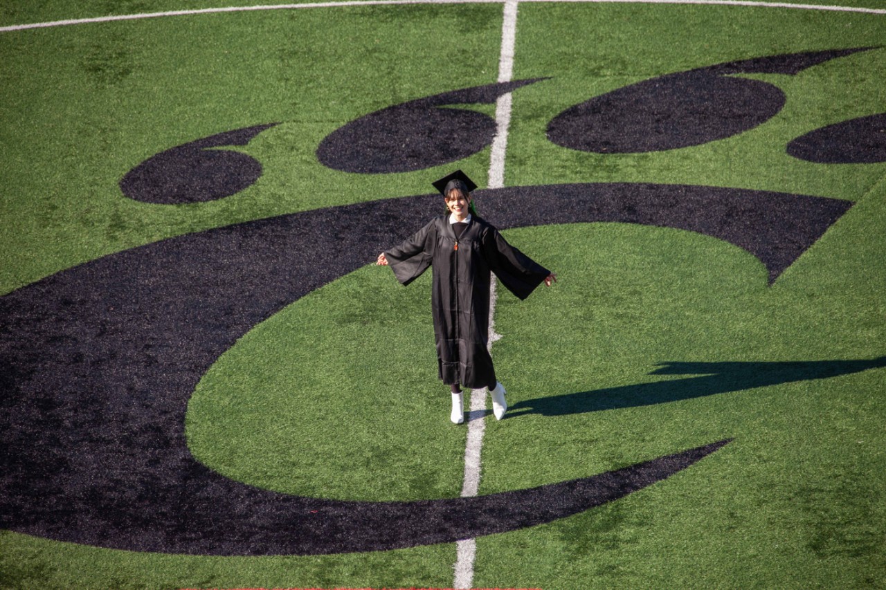 UC grad Sydney O'Connor stands in the Bearcat C-paw on the soccer field.