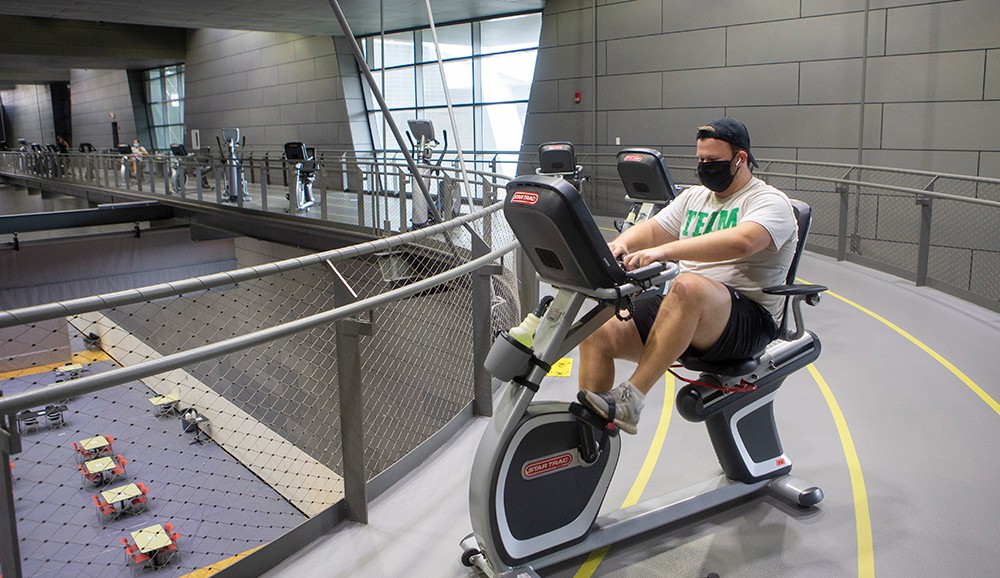 a man wearing a face mask exercises on an exercise bike 