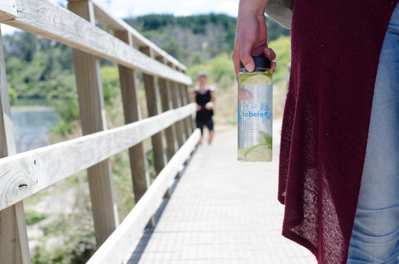 woman holding a water bottle walking across a bridge