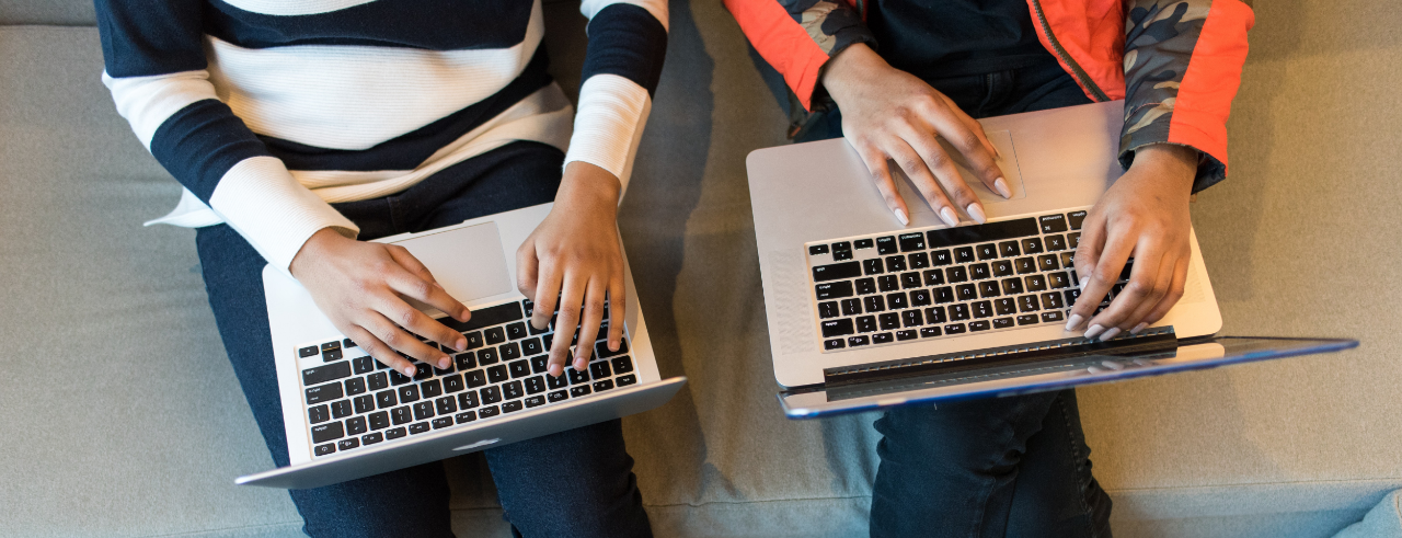 two women sitting with laptops in their laps