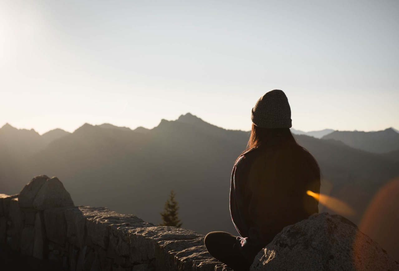 woman sitting watching a beautiful sunlit mountain top