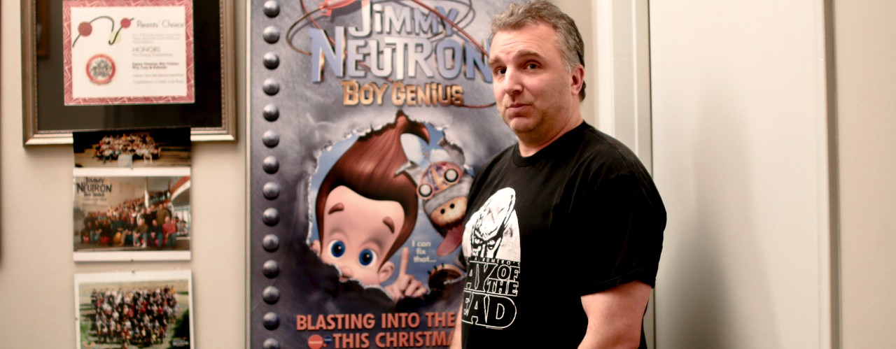 UC assistant professor Mike Gasaway stands in front of his Jimmy Neutron: Boy Genius poster.