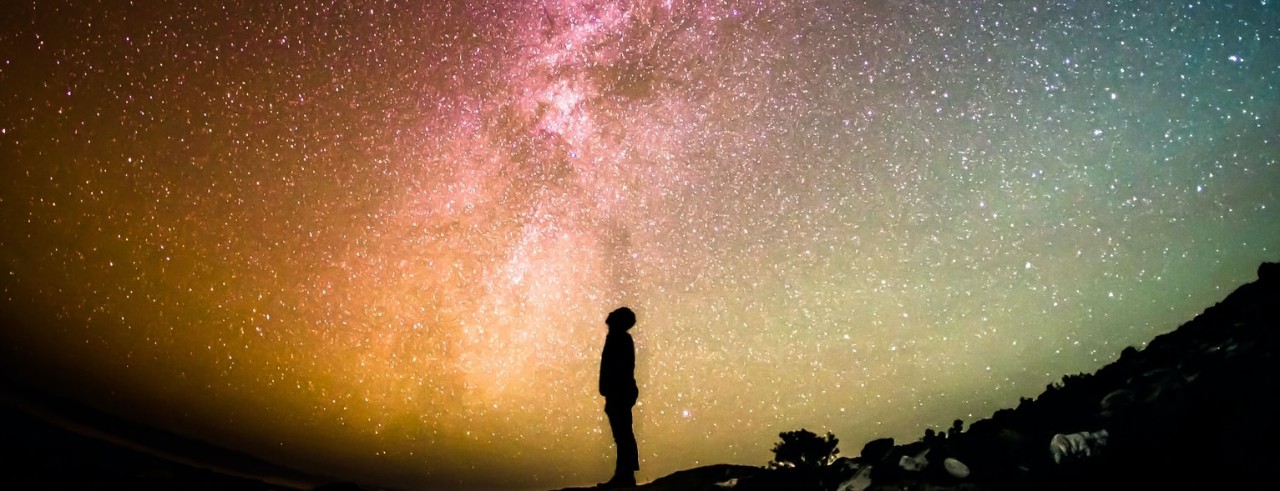 silhouette of person looking at starry night sky