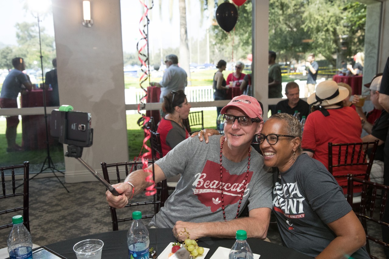 Man and woman in UC gear take a selfie with selfie stick
