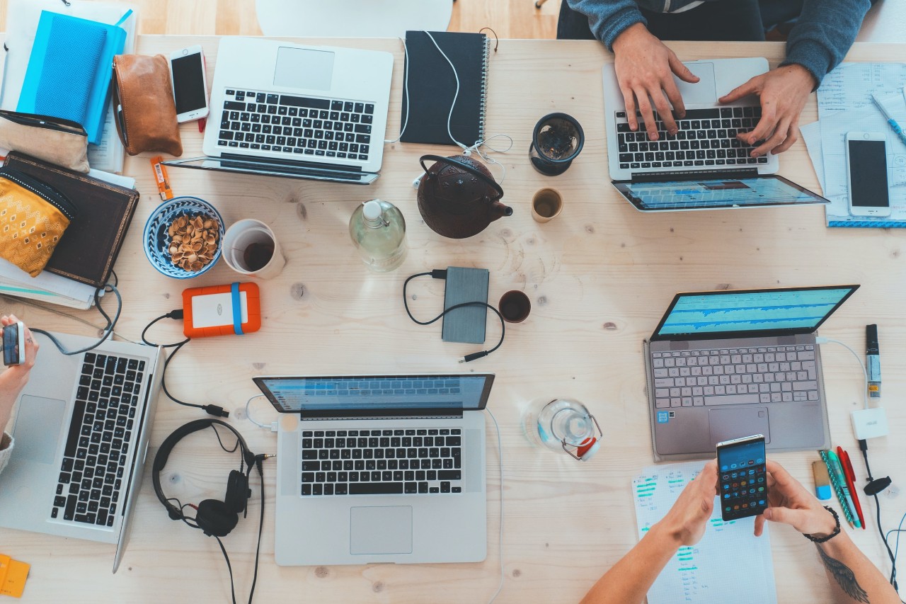 several lap tops and cell phones on a table 