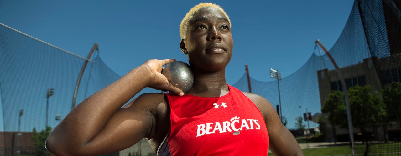 Annette Echikunwoke, UC Olympic hammer throw athlete stands holding a sport discus.