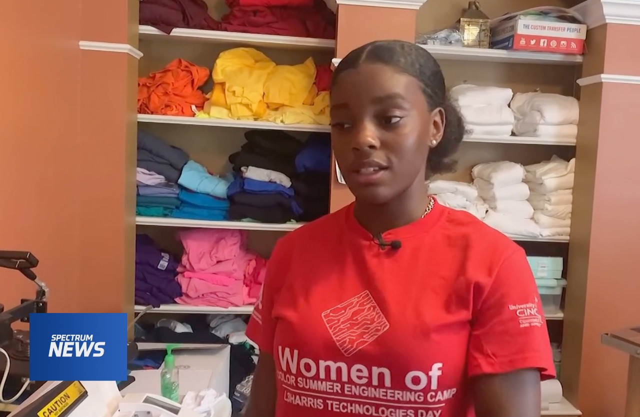 Mariah Couch stands in front of shelves of T-shirts at her design business.