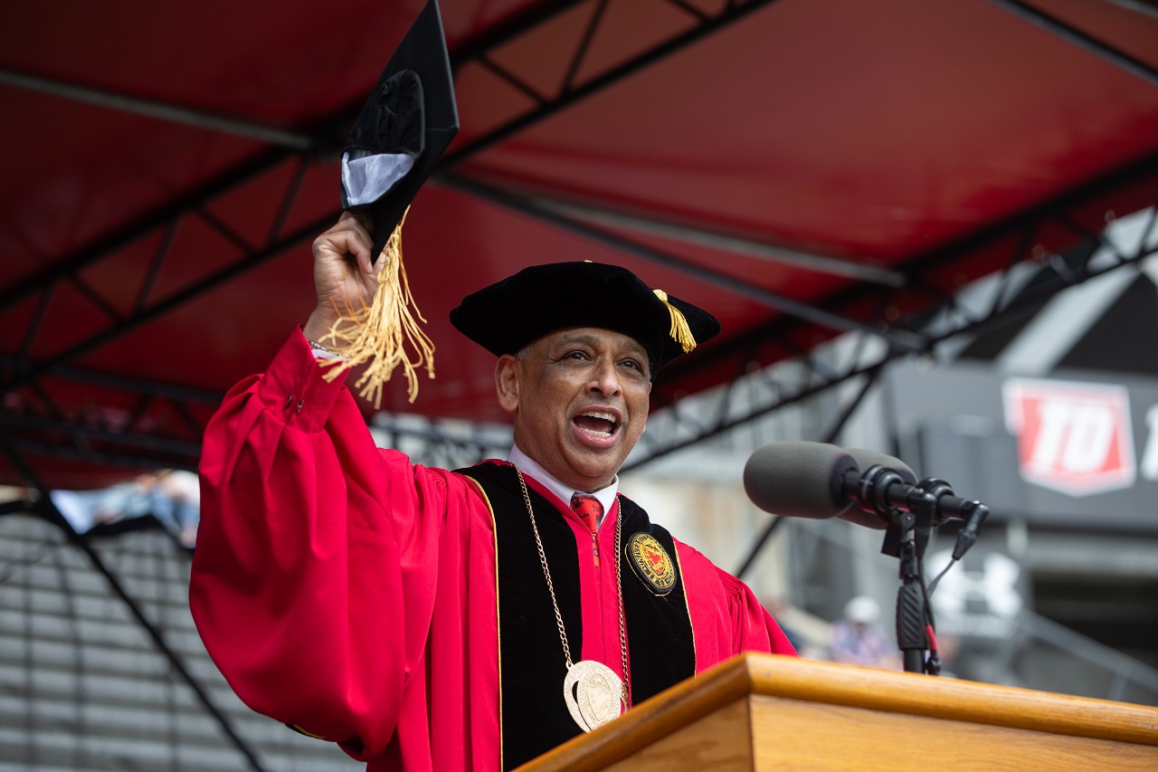 UC President Neville Pinto gives a commencement address in his cap and gown.