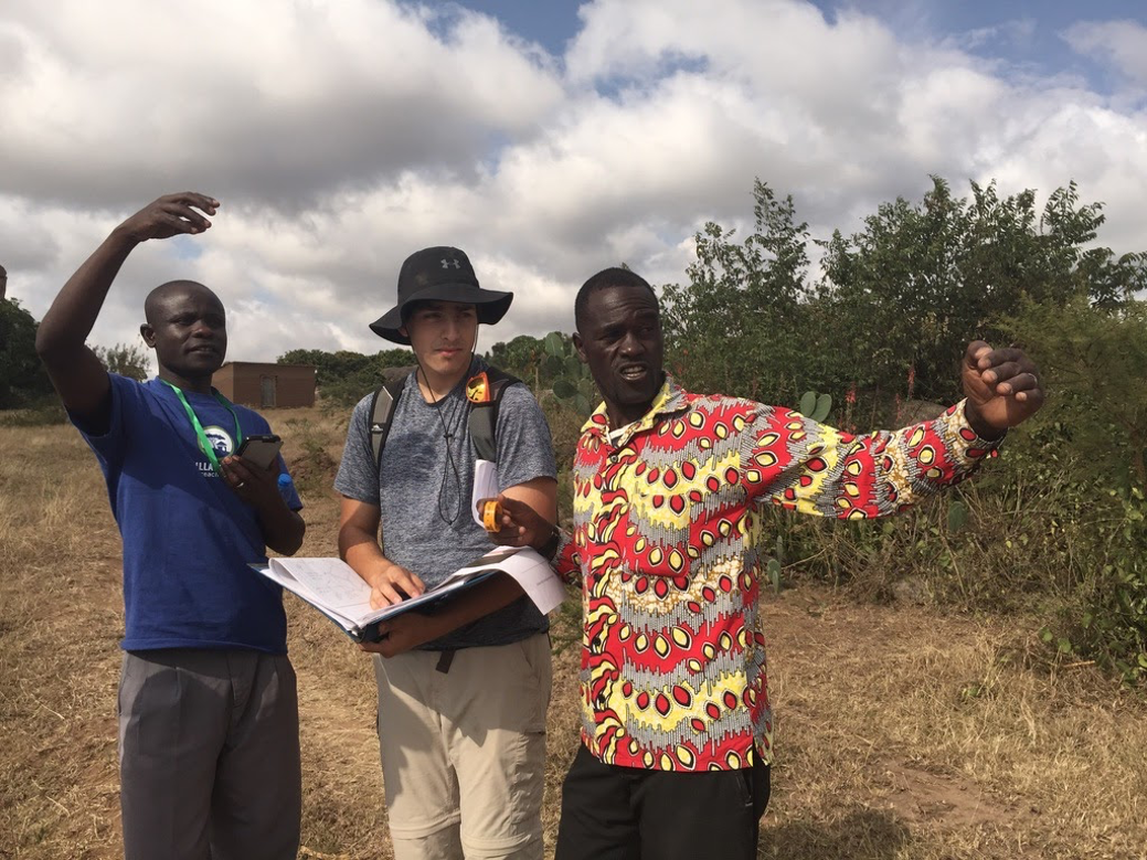 A student with two community members in Tanzania