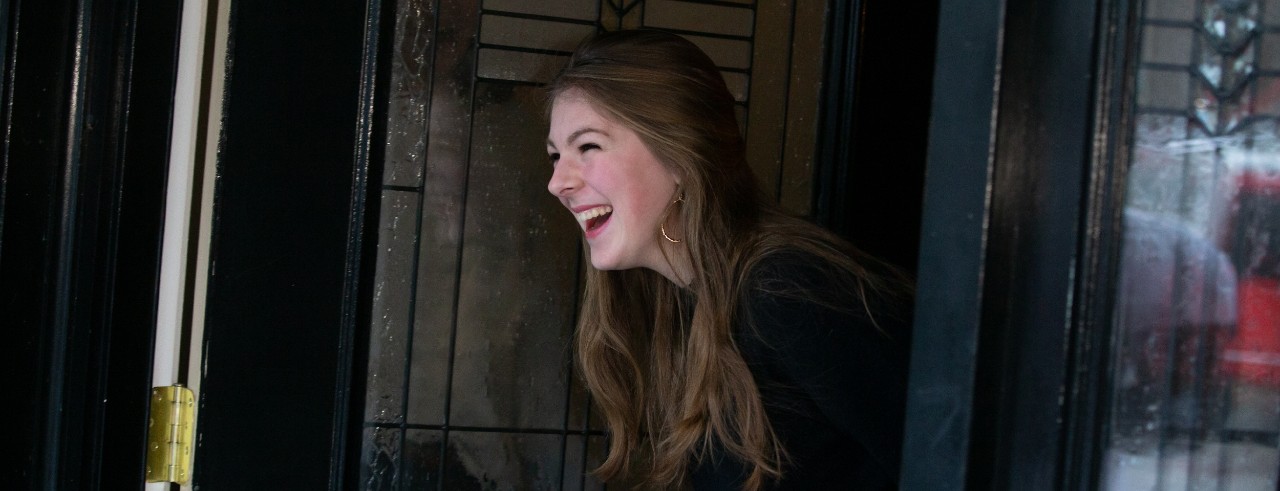 Young woman opening front door smiling