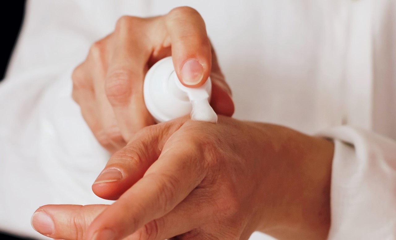 lotion being dispensed from bottle by male hands onto skin of his hands