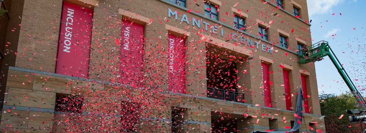 Dedication of Mantei Center on UC's campus. Red confetti in front of building.