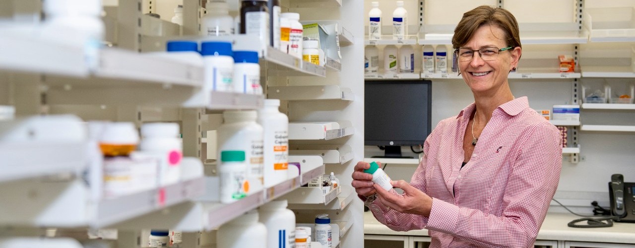 UC pharmacy professor Bethanne Brown stand among medications in a pharmacy